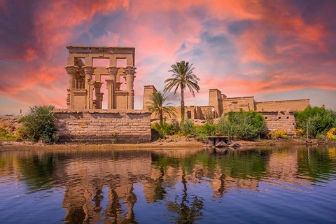 Incredible orange sunrise at the temple of Philae, a Greco-Roman construction seen from the Nile
