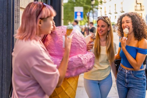 Girls having fun eating ice cream in the city standing in front of ice cream store with a giant