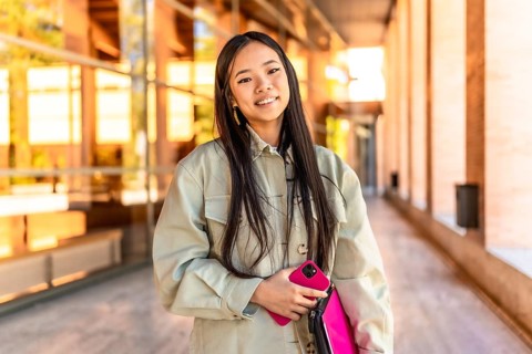 Portrait of a female beauty chinese cute university student standing with mobile phone and laptop