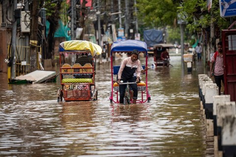 Commuters in cycle rickshaws as they wade through a flooded street after heavy rains in Guwahati,