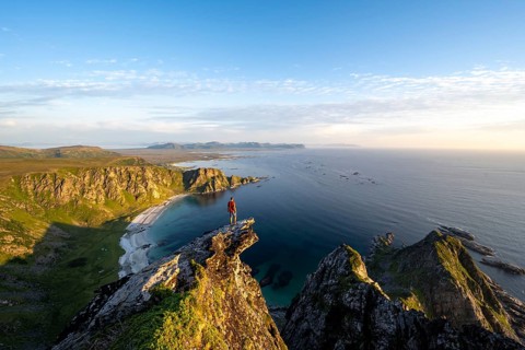 Evening mood, mountaineer standing on a rocky outcrop on the summit of Måtind, view of coastal