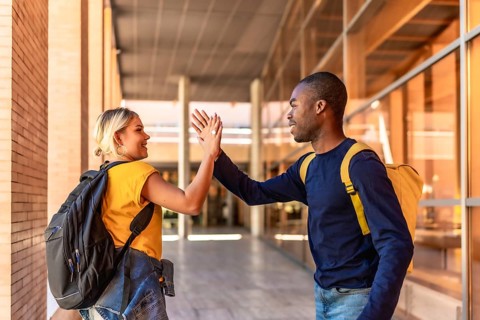 Multi-ethnic caucasian female and african male students high-fiving at the university
