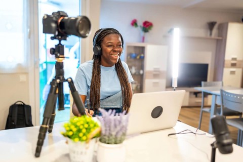 Young female content creator smiling and recording video with professional equipment in her living