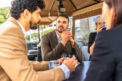 Business coworkers talking while drinking coffee during work break at cafeteria