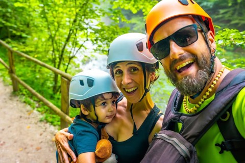 Happy family wearing helmets, taking a selfie at the vintgar gorge, a wooden footbridge in bled,