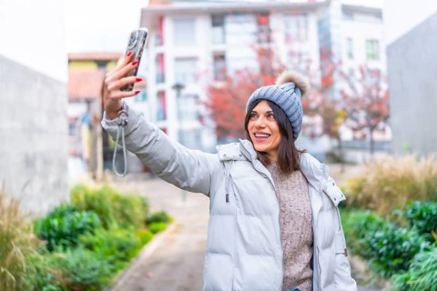 Beauty woman in winter clothes taking selfie with mobile phone in the city