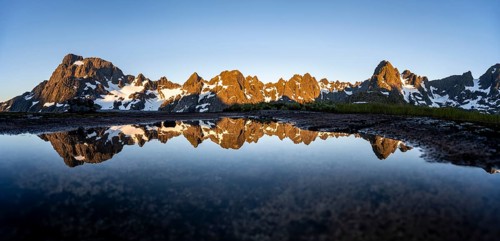 Rocky mountain peaks reflected in a small pond, mountain landscape with alpenglow at sunrise, at