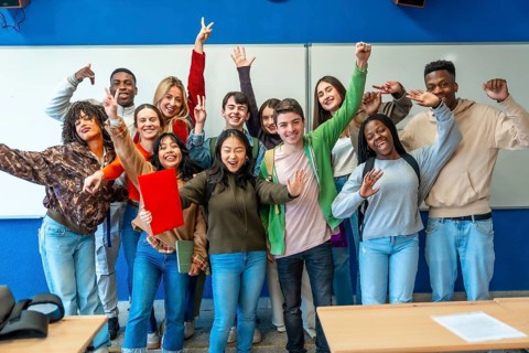 Multi ethnic university students celebrating their academic achievements inside classroom