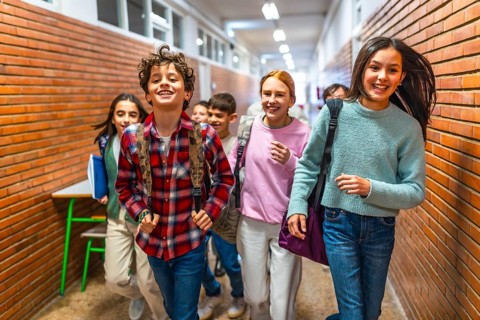 Cheerful students running through the school hallway, filled with laughter and excitement, enjoying