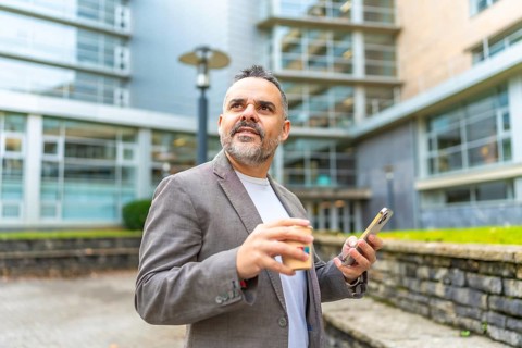 Mature caucasian businessman using phone during coffee break outside the office enjoying fresh air