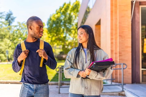 Multi-ethnic african and chinese exchange students talking walking along university campus
