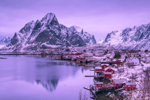 Fishermen's Village in front of snowy mountain range at the coastline in winter, Lofoten, Norway,
