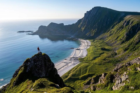 Climber on a rock, view of picturesque coastal landscape, steep coast with peak Måtind or Måtinden,