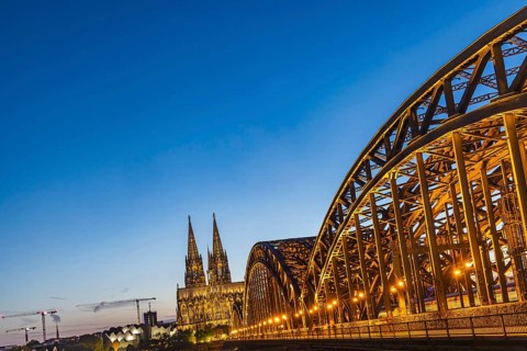 Cologne Cathedral, illuminated in the evening. Hohenzollern Bridge, railway bridge over the Rhine.