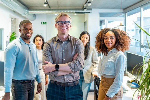 Diverse team of professionals standing together in a modern coworking office, showcasing teamwork
