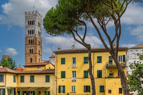 Winding houses with pastel-coloured facades, behind the tower of San Martino Cathedral, historic