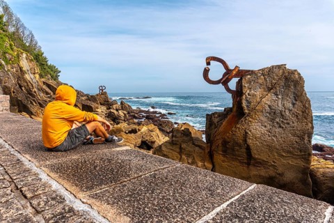A young man in a yellow sweatshirt visiting the Peine del Viento in San Sebastián. Province of