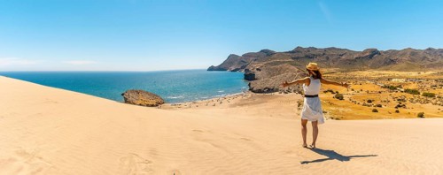 Panoramic photo of a woman enjoying views of the ocean in Cabo de Gata, Spain, Europe