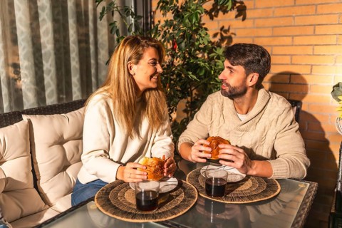 Young couple enjoying a cozy meal and drinks on their balcony, soaking in the warm summer evening
