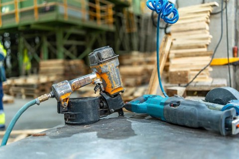 Close-up photo with no people of a compressed air machine gun in a pallet recycling plant workshop