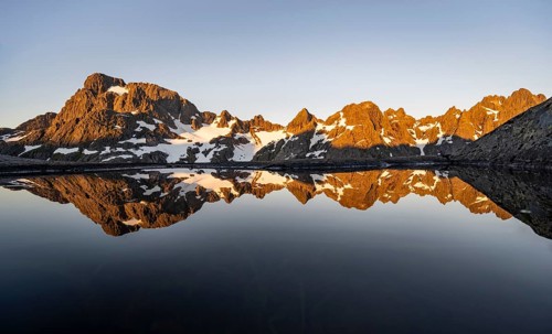 Rocky mountain peaks reflected in a small pond, mountain landscape with alpenglow at sunrise, at