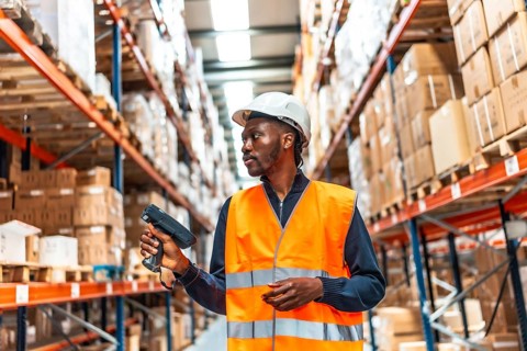 African man scanning parcels doing inventory with wireless scan in a warehouse
