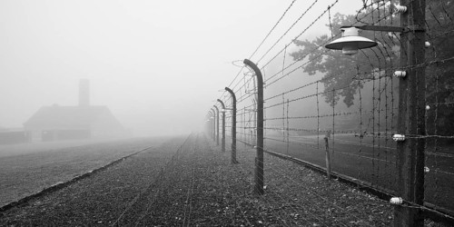 Reconstructed camp fence with crematorium in the fog at beech forest concentration camp, now a
