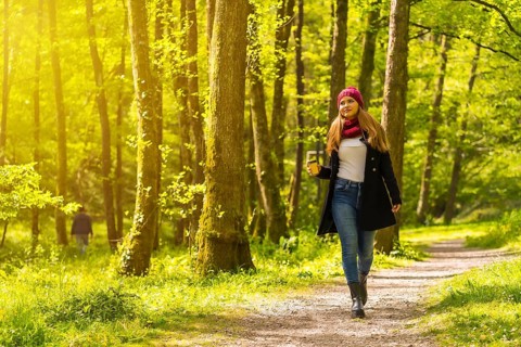 Latin girl with a black jacket, scarf and red woolen hat enjoying in an autumn park, walking along