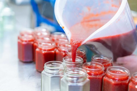 Strawberry mixture is filled into jars from a large measuring cup, jam production, Haselstaller