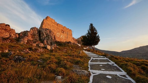 Warm evening light, path leading to a ruin with a single tree under a clear sky, Archangelos,