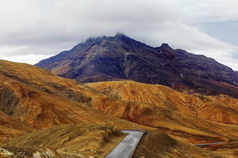 A winding road leads through a mountainous landscape under a cloudy sky, Pajara, Fuerteventura,