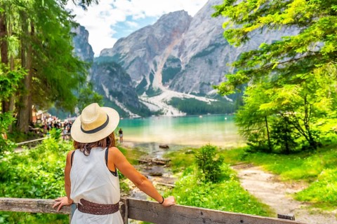 Tourist enjoying breathtaking view of lake braies, surrounded by majestic mountains and lush