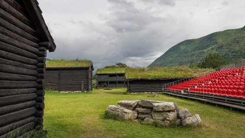 Traditional wooden houses with grass sod roofs, rows of seats with red plastic chairs, ready for an