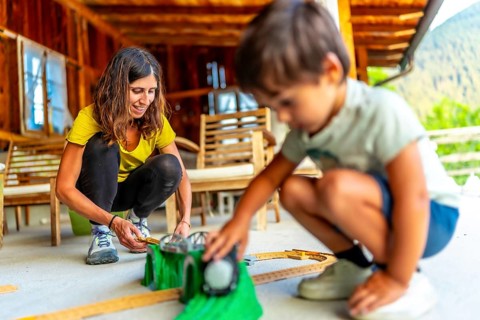 Mother and son enjoying quality time together, building toy train tracks on a porch