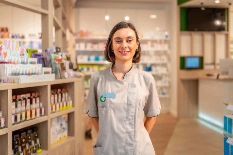Portrait of a young woman pharmacist standing with hands on back in the store