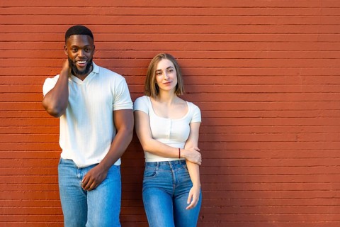 Horizontal photo with copy space of a shy multi-ethnic couple in denim clothes leaning on urban