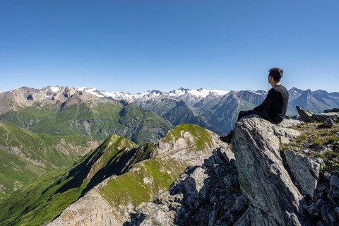 Mountaineer sitting on a rock in front of a mountain panorama with Großvenediger, mountain