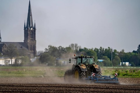 A tractor works a field, due to long dryness in spring, no rain for more than 4 weeks, the fields