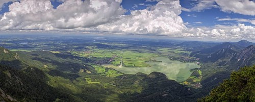 Panoramic view from Herzogstand down to a mountain landscape with Lake Kochel and cloudy sky,