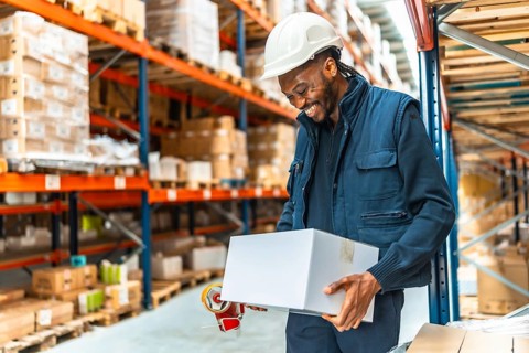 Happy african man worker preparing parcels to deliver in a warehouse