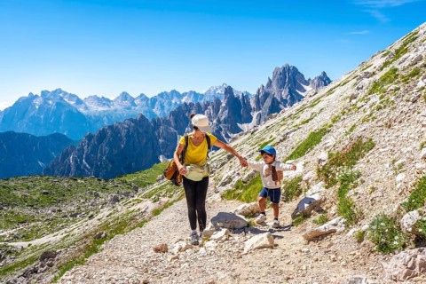 Tourists enjoying a summer hike on a mountain trail in the italian dolomites, with the tre cime di