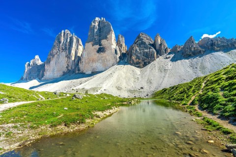 Scenic view of tre cime di lavaredo and its reflection in a mountain lake during a sunny summer day
