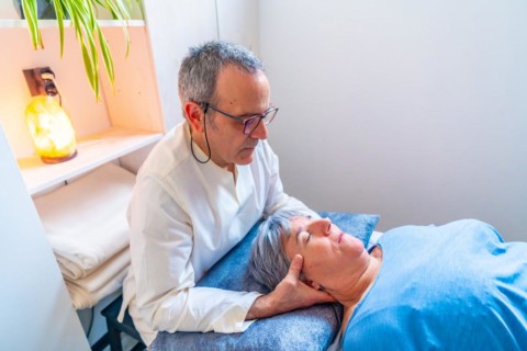 Mature male therapist doing an oriental neck massage to a mature woman in a clinic