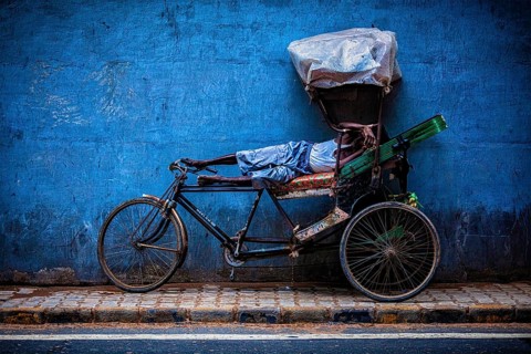 DELHI, INDIA, SEPTEMBER 11, 2011: Indian cycle rickshaw driver sleeping on his bicycle in the