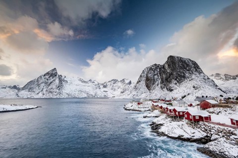 Rorbuer cabins of Hamnoy by the fjord, snowy mountains in the back, Hamnøy, Reine, Moskenesøya,