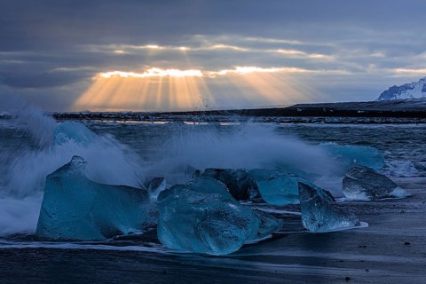 Waves breaking on icebergs on the black beach of Breidamerkursandur, sunset, near Jökullsarlon,