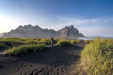 Tourist on a sand dune, Black beach with volcanic sand, Sand beach, Dunes with grass, Stokksnes