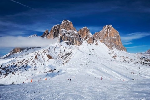 View of a ski resort piste with people skiing in Dolomites in Italy