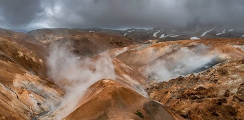 Steaming streams between colourful rhyolite mountains with snowfields, Hveradalir geothermal area,
