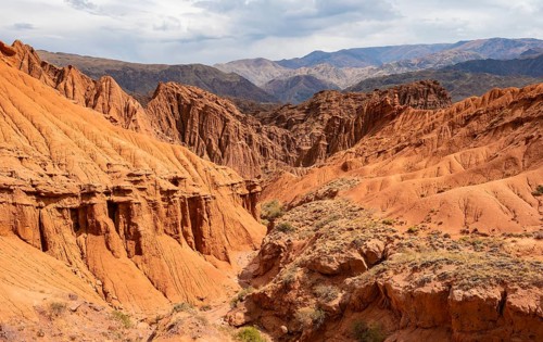Eroded mountain landscape with sandstone cliffs, canyon with red and orange rock formations,